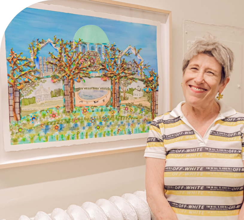 A person with short hair, visible from the mid-torso up and wearing a short sleeved striped shirt with a collar smiles at the camera in front of a framed collage depicting a green dome behind trees.