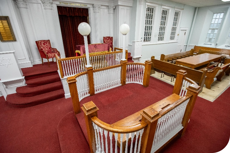 View of the chapel's center reading area and bima with red velvet ark curtain