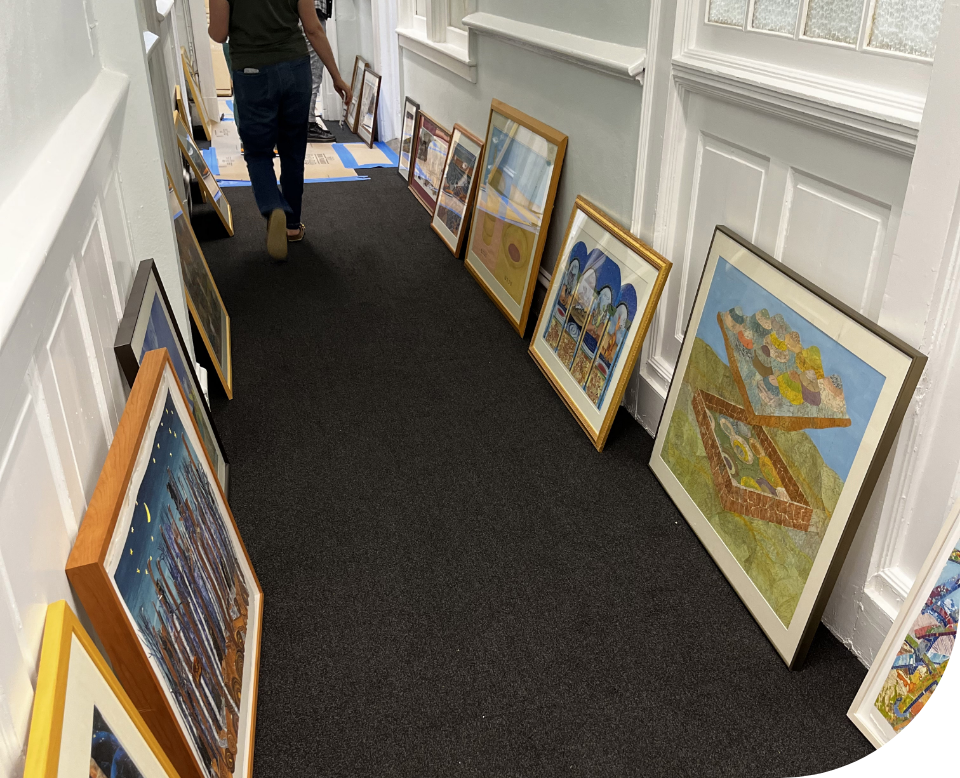 Framed artwork lined up and leaning against the wall on either side of a long hallway in Third Space.