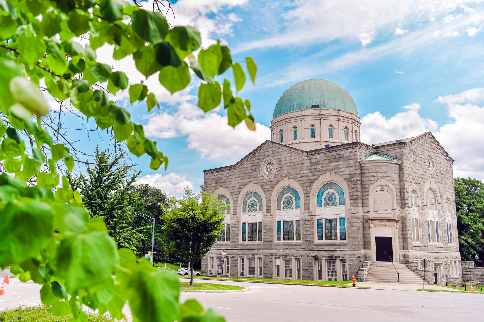 Exterior of Third Space from Across the street with view of entrance and dome, a tree branch with green leaves in the foreground