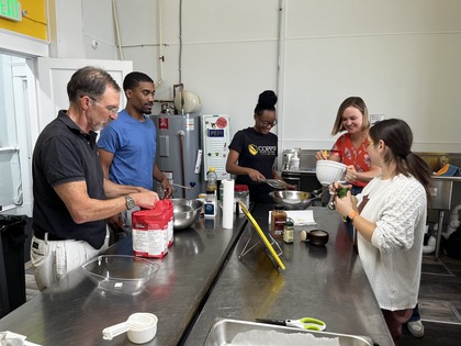 A group of people work at a stainless steel cook top