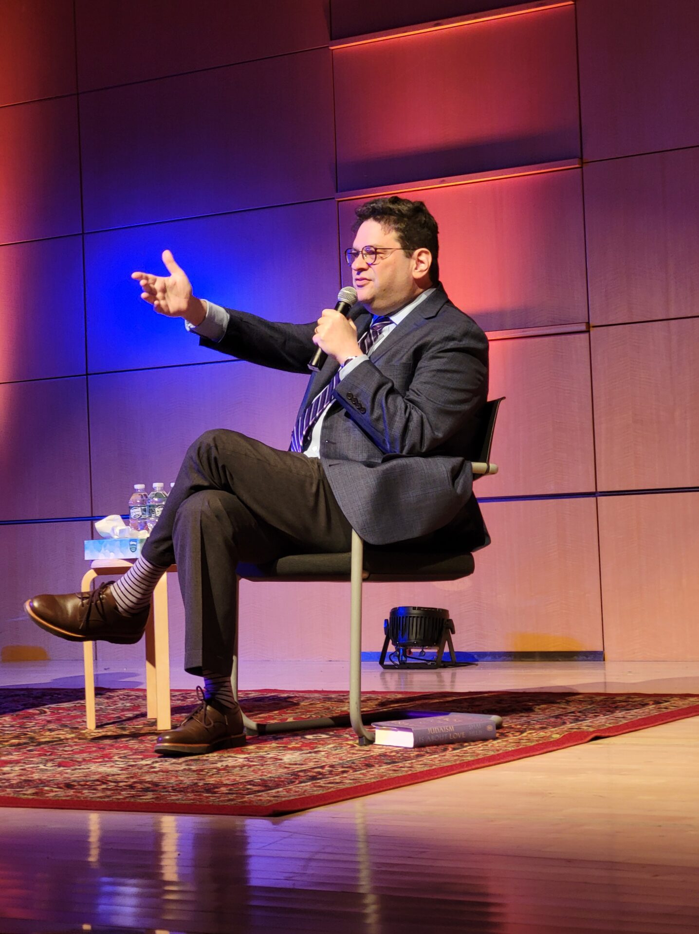 Rabbi Shai Held seated on stage speaking into a microphone and gesturing toward audience