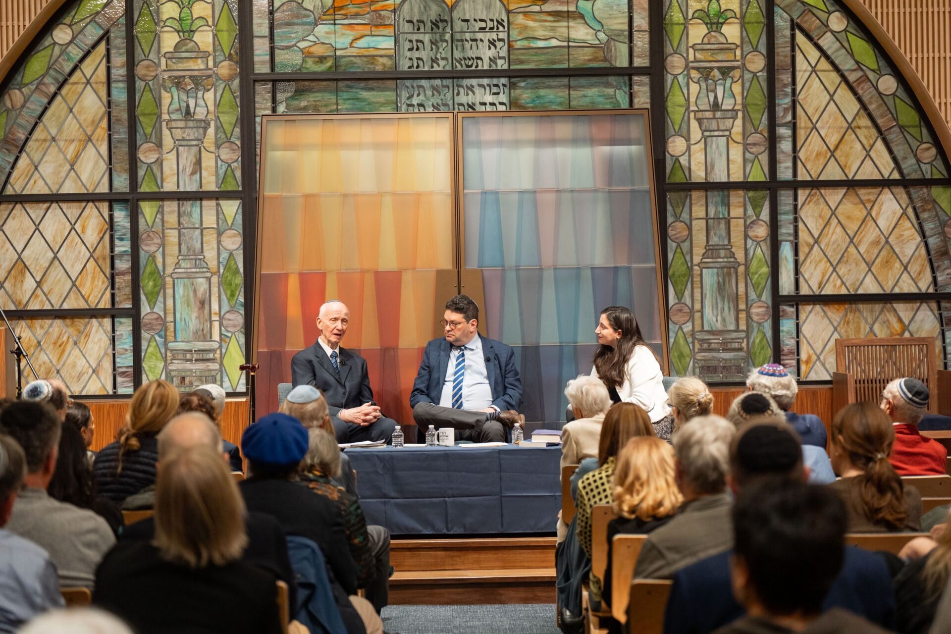 Rabbi Shai Held on stage with an older man on his right and a woman on his left